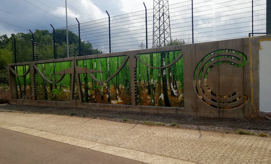 Stützwand am Umspannwerk: gemalter Birkenwald hinter gemalten Beton-Ornamenten