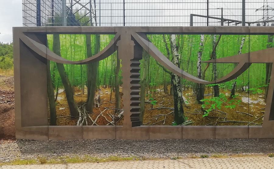 Linker Mauerbeginn: Birkenwald hinter gemalten Beton-Ornamenten, Illusionsmalerei