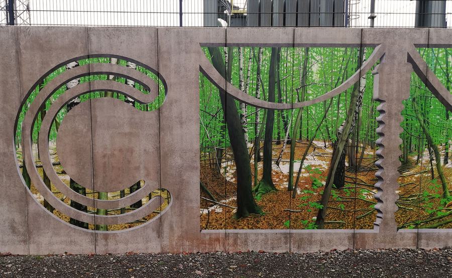 Mitte der Wand: das „C“ aus dem Creos-Logo als gemaltes Beton-Relief