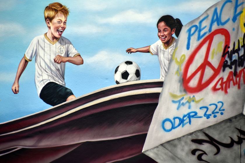 Fußball spielende Kinder und „Peace“-Quader